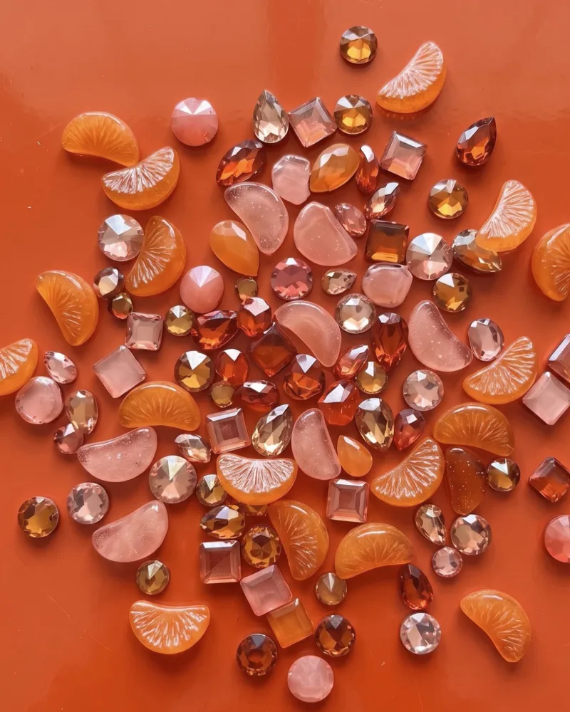 Orange candy slices with amber and pink gems on an orange surface